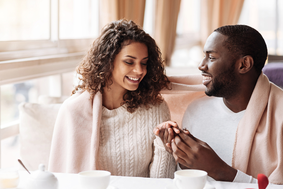 a man placing an engagement ring on a woman's finger