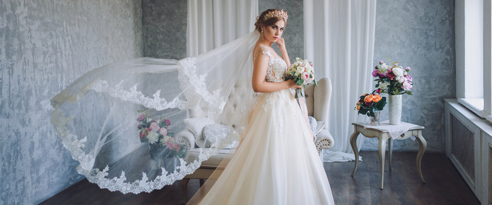Young attractive Asian couple, man wearing white shirt, woman wearing white dress with wedding veil holding bouquet of flowers together. Concept for pre wedding photography.